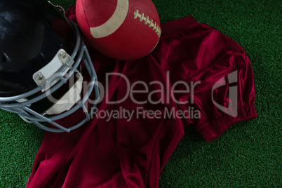 American football jersey, head gear and football lying on artificial turf