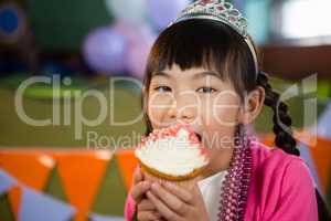 Girl having cupcake during birthday party at home