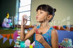 Girl playing with bubble wand during birthday party