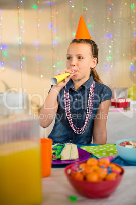 Girl blowing party horn during birthday party