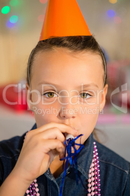 Girl blowing party horn during birthday party