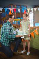 Father giving surprised birthday cake to her daughter