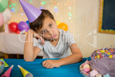 Boy sitting near a birthday cake at home