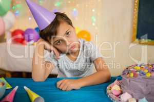 Boy sitting near a birthday cake at home