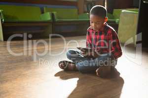 Boy sitting on wooden floor using digital tablet