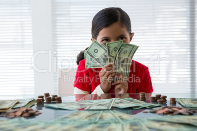 Happy girl holding currency at desk in office