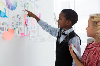 Businessman explaining to female colleague over whiteboard in office