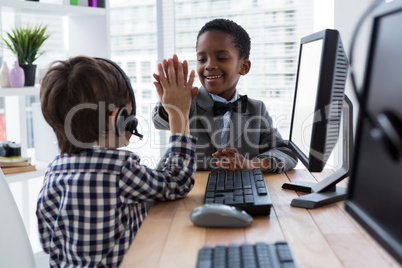 Male colleagues giving high five at desk