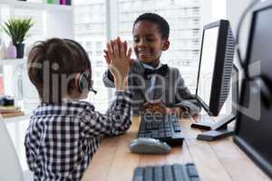Male colleagues giving high five at desk