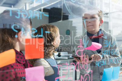 Business people analyzing data at office seen through glass