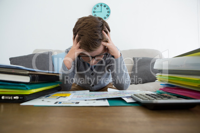 Frustrated businessman with head in hands sitting on sofa