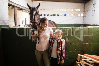 Sisters talking while standing by horse