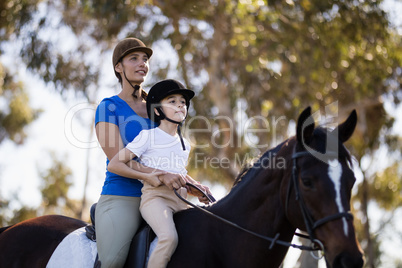 Woman teaching horseback riding to girl