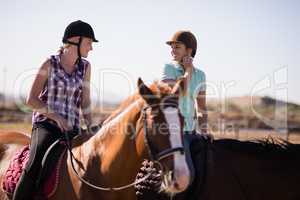 Happy female friends talking while horseback riding