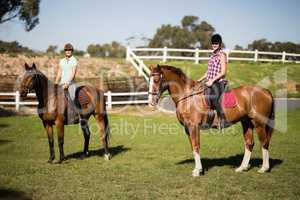 Female friends horseback riding during sunny day