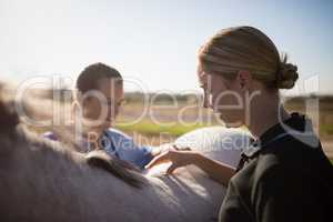 Female jockey with vet examining horse