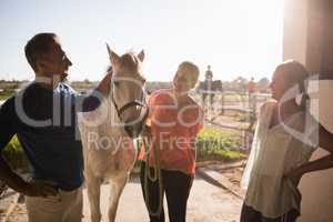 Trainer talking to women while standing by horse