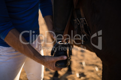 Midsection of male trainer adjusting woman leg on stirrup