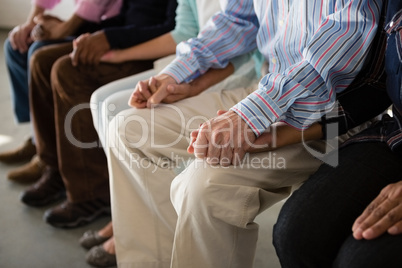 Senior friends holding hands while sitting on chair