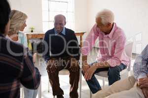 Happy senior friends talking while sitting on chair