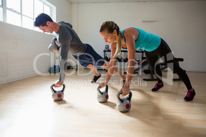 Athletes doing pushups with kettlebells in gym