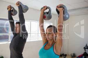 Confident male trainer with athlete lifting kettlebells