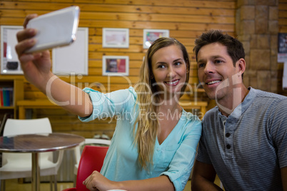 Woman taking selfie with boyfriend through mobile phone in cafe