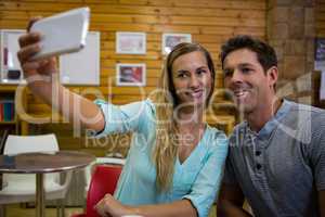 Woman taking selfie with boyfriend through mobile phone in cafe