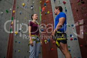 Trainer training female athlete in climbing wall at gym