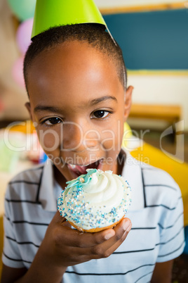 Portrait of cute boy having cupcake during birthday party