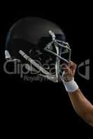 American football player holding a head gear raised