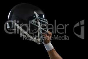 American football player holding a head gear raised