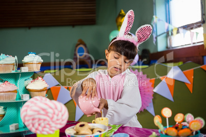 Girl pouring coffee into cup during birthday party