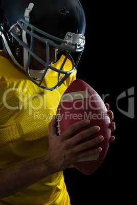 American football player holding a football with both his hands