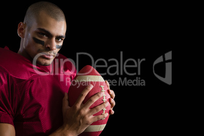 Determined American football player holding a football with both his hands