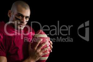 Determined American football player holding a football with both his hands