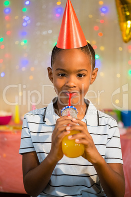 Portrait of happy boy drinking juice during birthday party