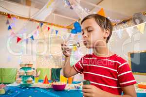 Cute boy playing with bubble wand during birthday party