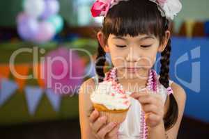 Cute girl decorating cupcake during birthday party