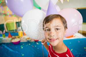Cute boy holding colorful balloons during birthday party