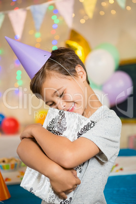 Boy embracing gift box during birthday party