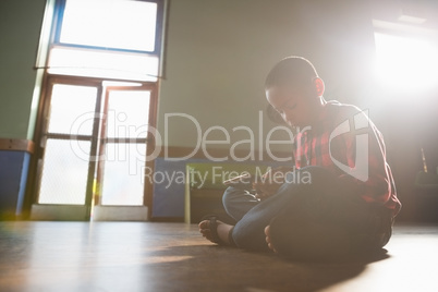 Boy sitting on wooden floor using digital tablet