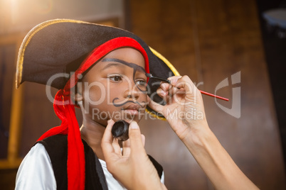 Hand of woman drawing on boy face