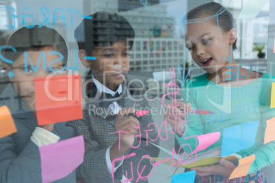 Colleagues discussing while writing on window seen through glass