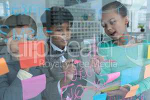 Colleagues discussing while writing on window seen through glass