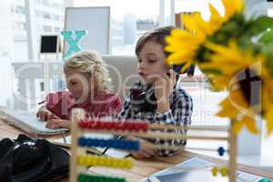 Businesswoman using computer while coworker talking on phone in office