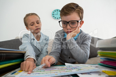 Colleagues discussing documents while sitting on sofa