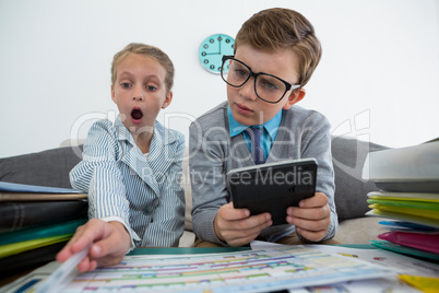 Businessman using digital tablet while surprised colleague analyzing files