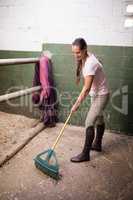 Female jockey cleaning stable