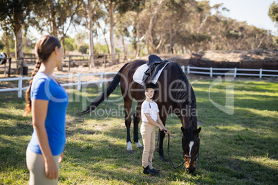 Side view of female jockey looking at sister standing by horse